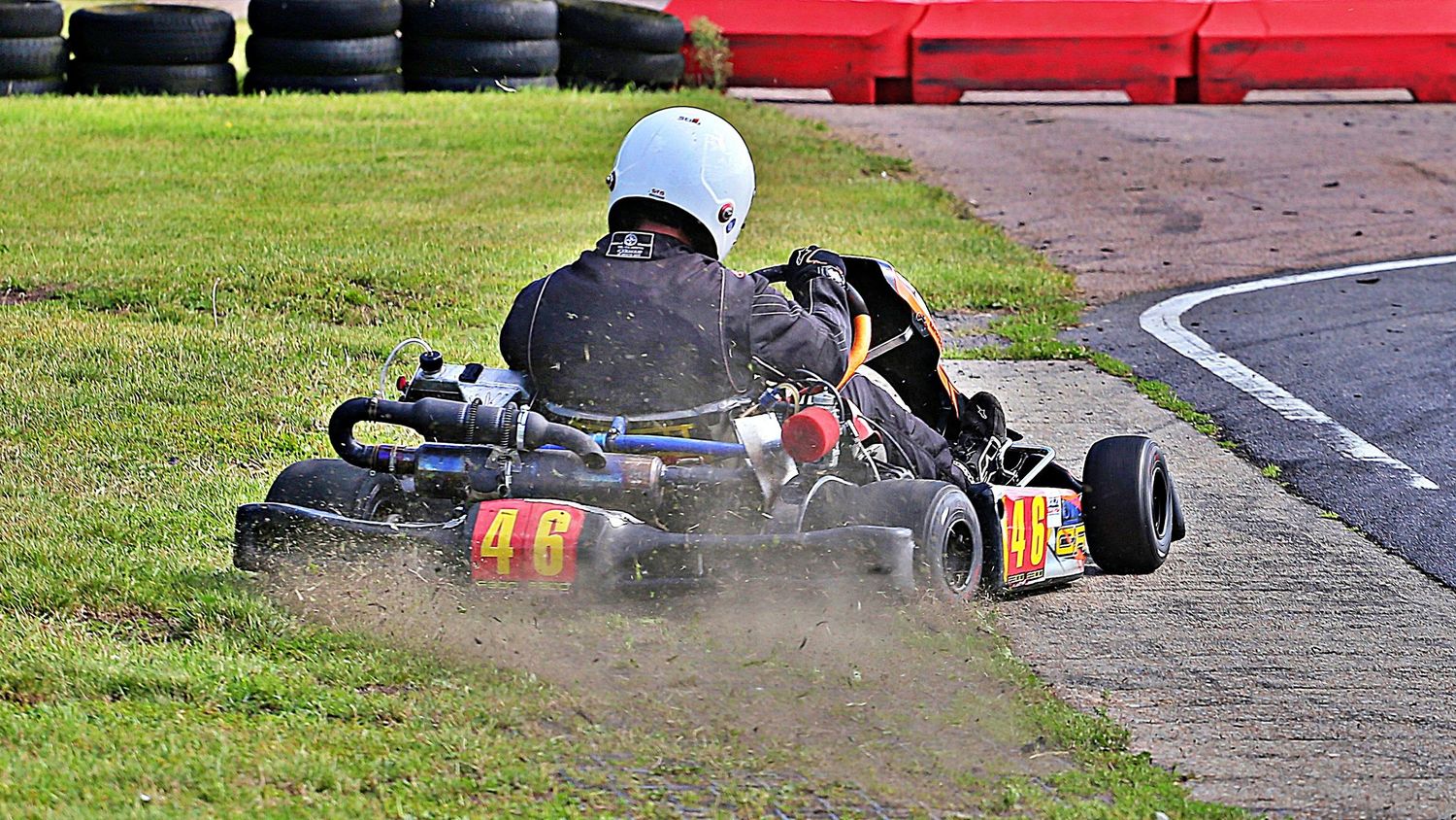 Go-kart racer number 46 navigating a dirt corner on a racing circuit during a competitive karting event.