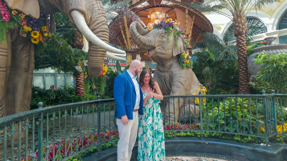 Couple kissing among elephant sculptures and tropical flowers inside the Bellagio conservatory in Las Vegas.