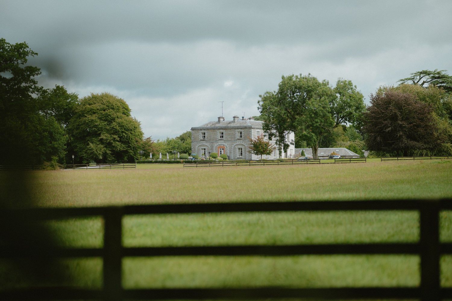 Tankardstown House and its lawns beneath a dramatic cloudy sky.