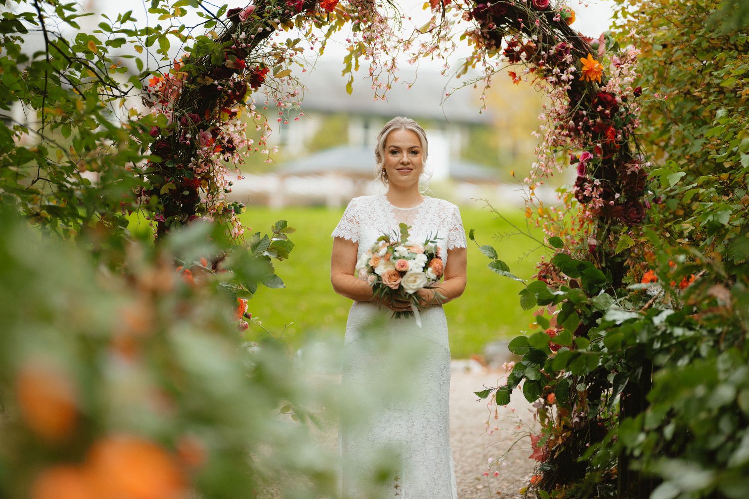 Bride beneath a flower-covered arch in the gardens at BrookLodge.