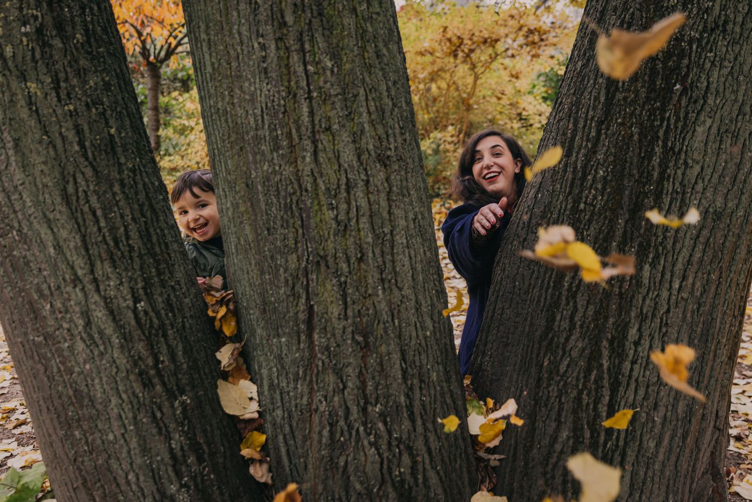 Lors d'une séance photo mère-fils en automne, les modèles s'en prennent à la photographe en lui lançant des feuilles mortes depuis un arbre