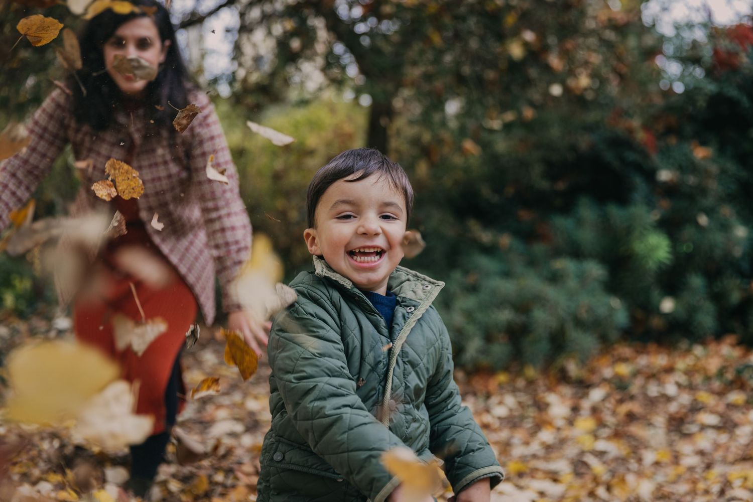 Mère et fils se poursuivent en se lançant des feuilles mortes dans un parc de Courbevoie en automne