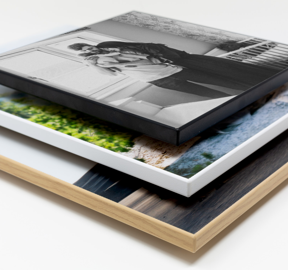 Stack of professional photo prints showcasing different mounting options with wood and acrylic materials.