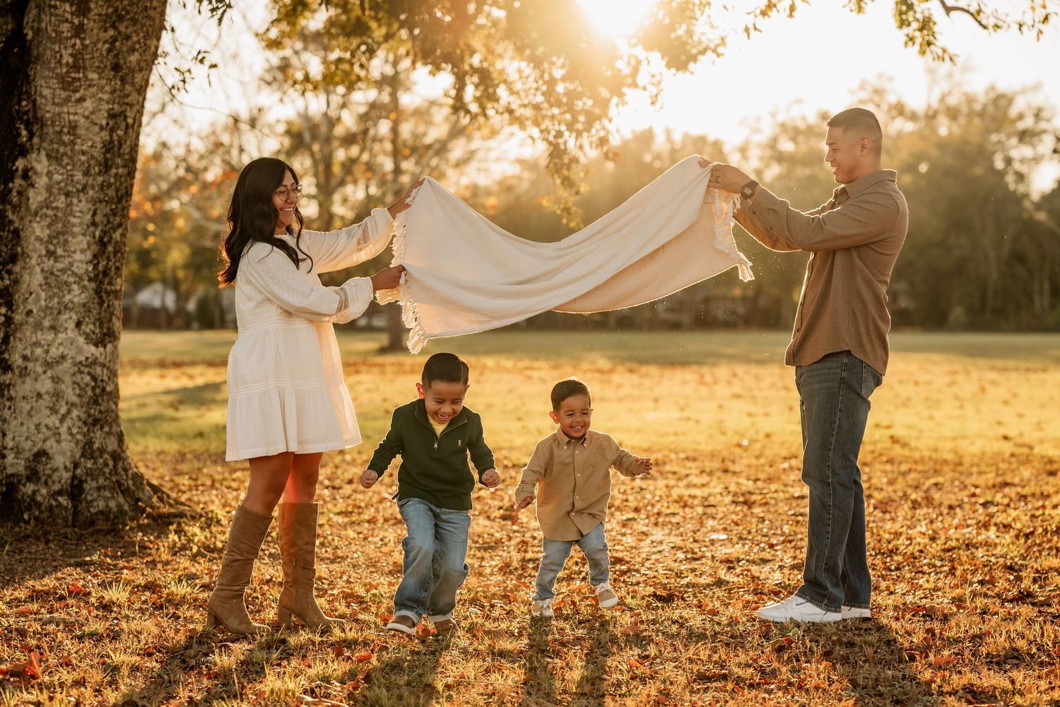 Parents playing with their two young sons during a sunset family photography session in Pensacola, Florida