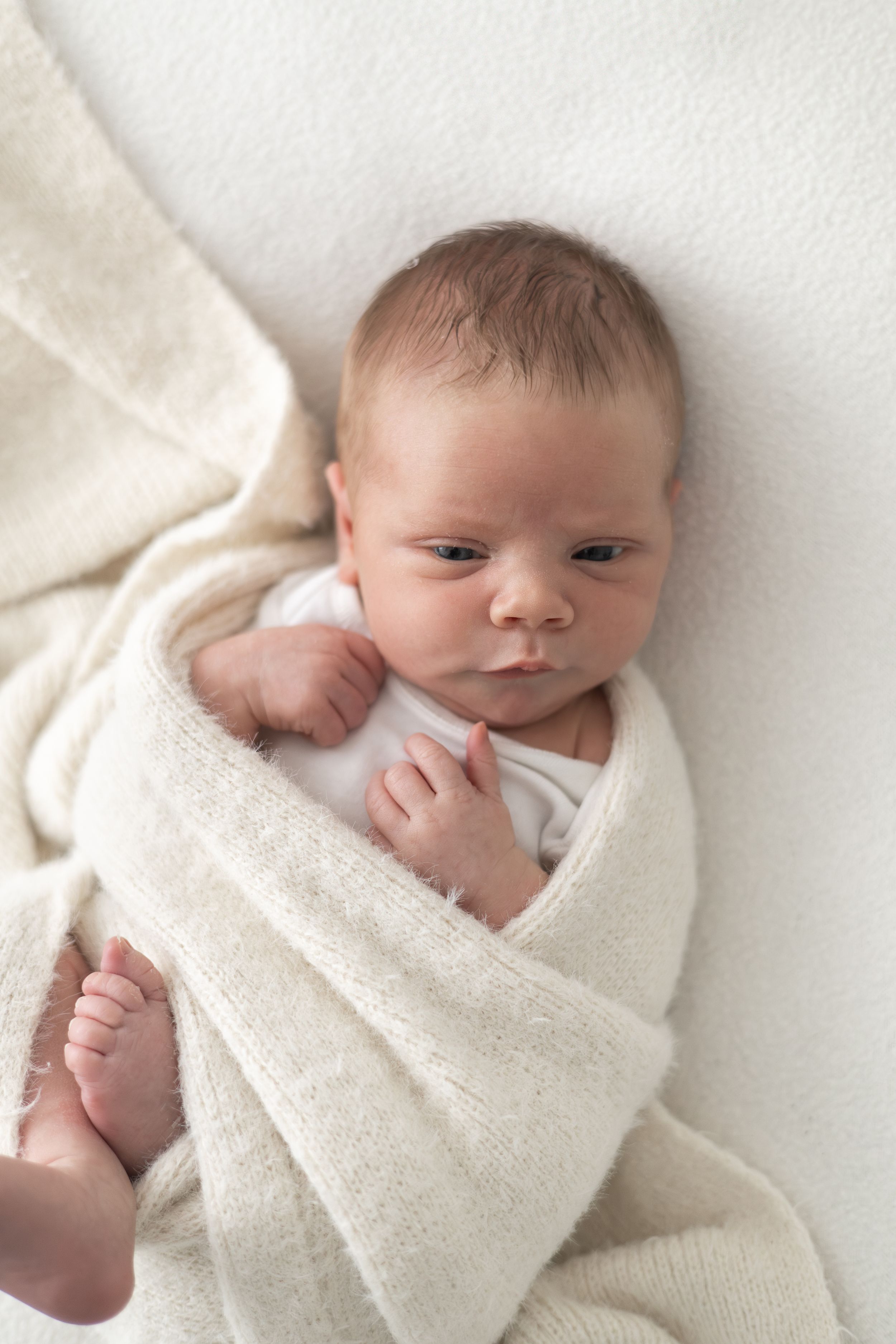 Newborn baby awake and making a small facial expression during their photoshoot