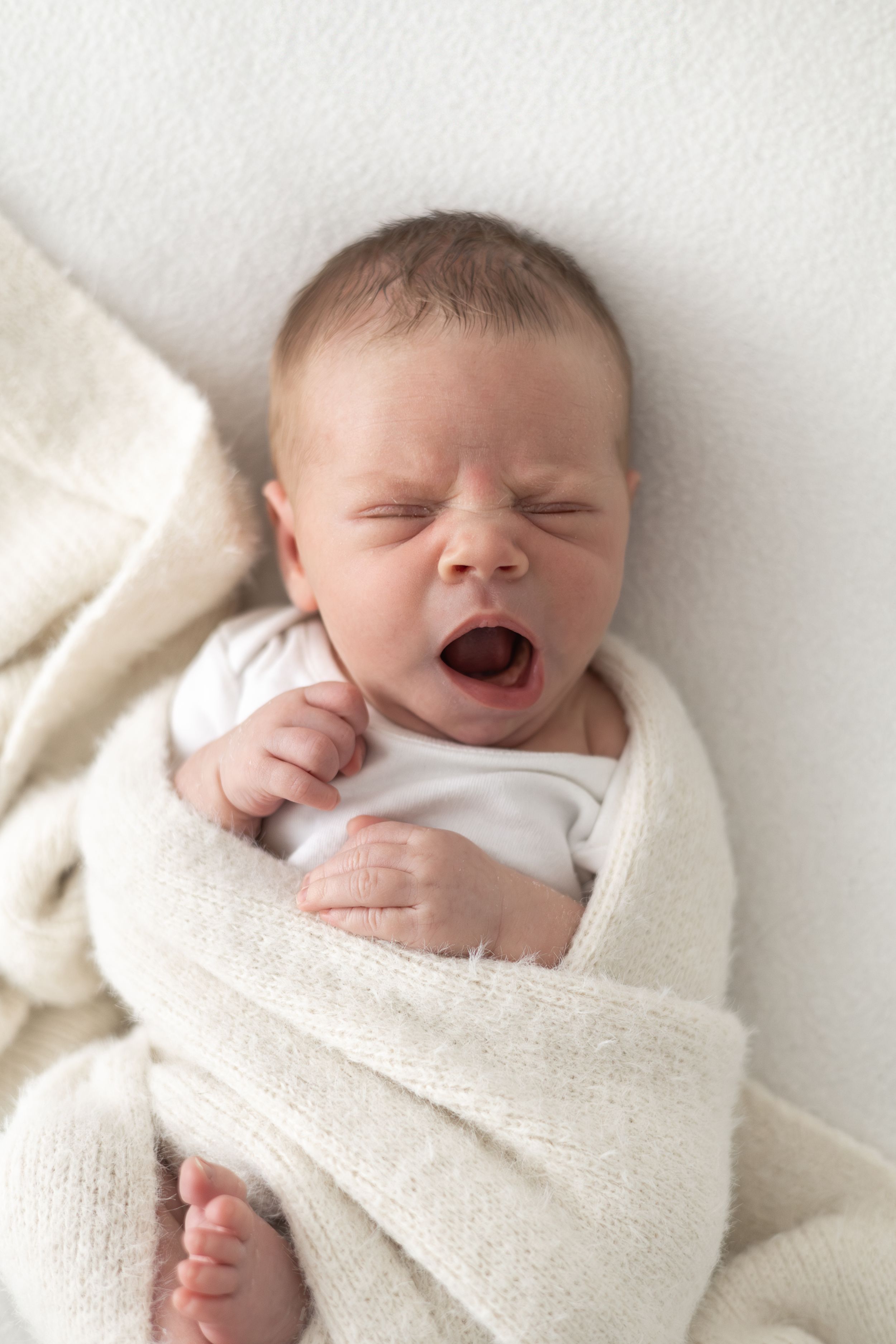 Newborn baby yawning during a relaxed natural photography session