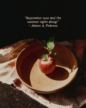 A red apple with leaves rests in a wooden bowl beside a James A. Pearson autumn quote on dark background.
