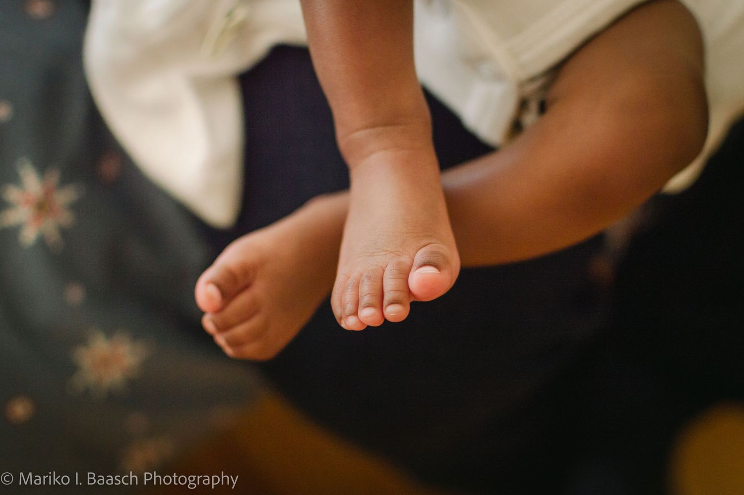 Close-up of tiny newborn baby feet dangling during a lifestyle newborn photography session at home.