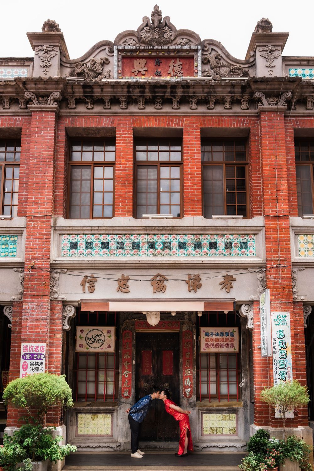 Traditional red brick Chinese building facade with ornate decorations and a person entering through the main doorway.