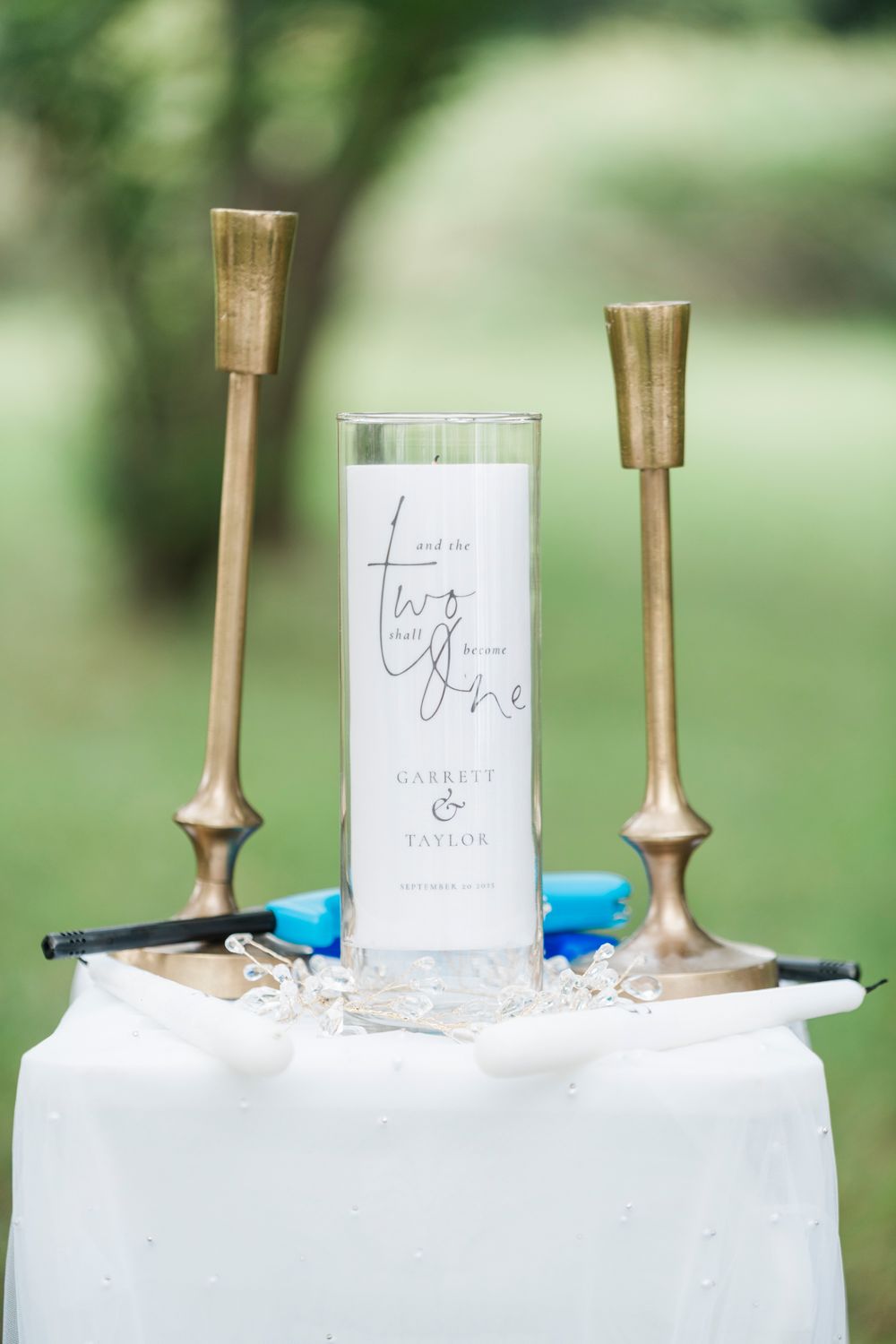 Unity candle ceremony setup with gold candlesticks and personalized cylinder candle for Garrett and Taylor's wedding.