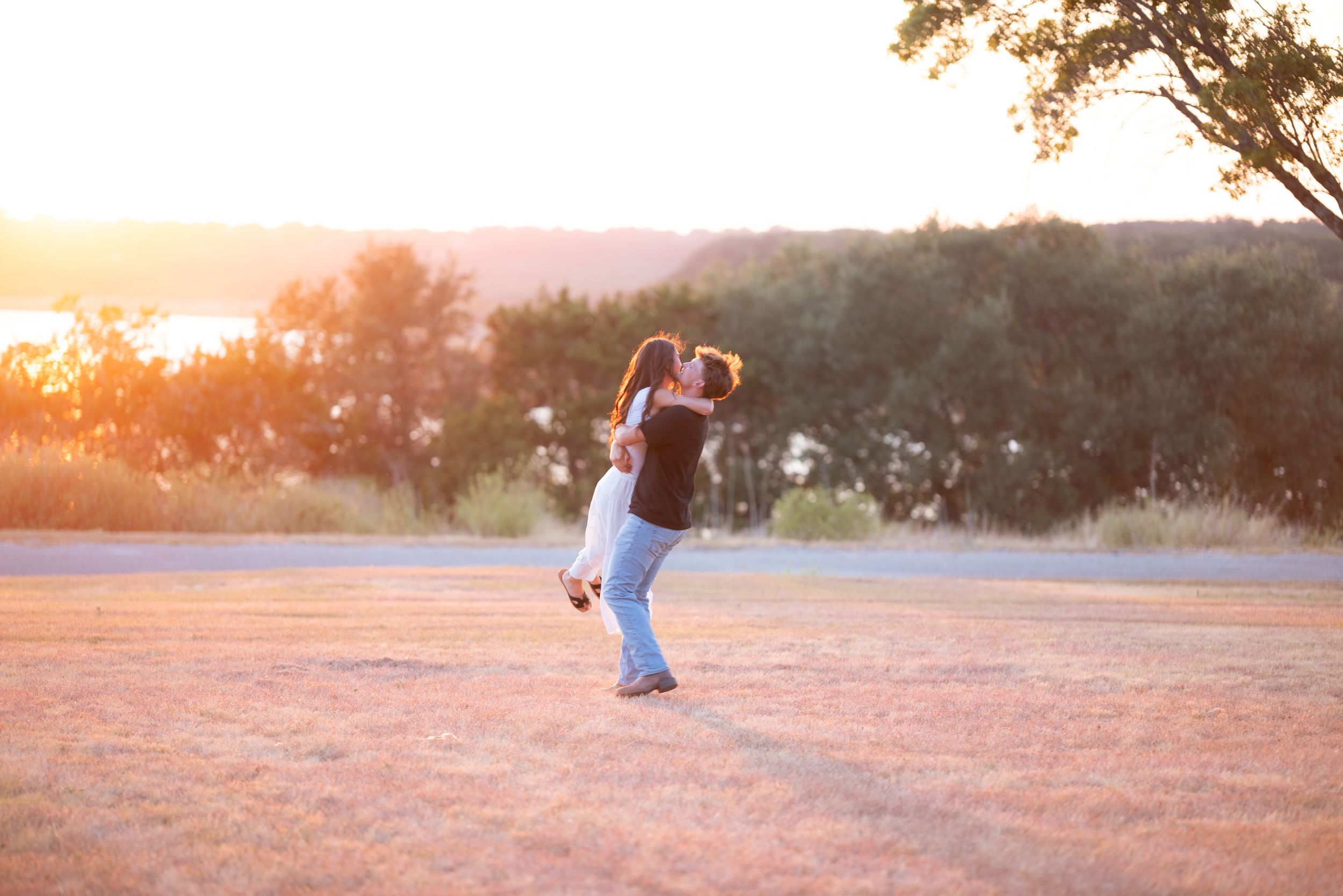 Couple embracing and spinning together in an open field during a warm golden sunset in Belton Texas