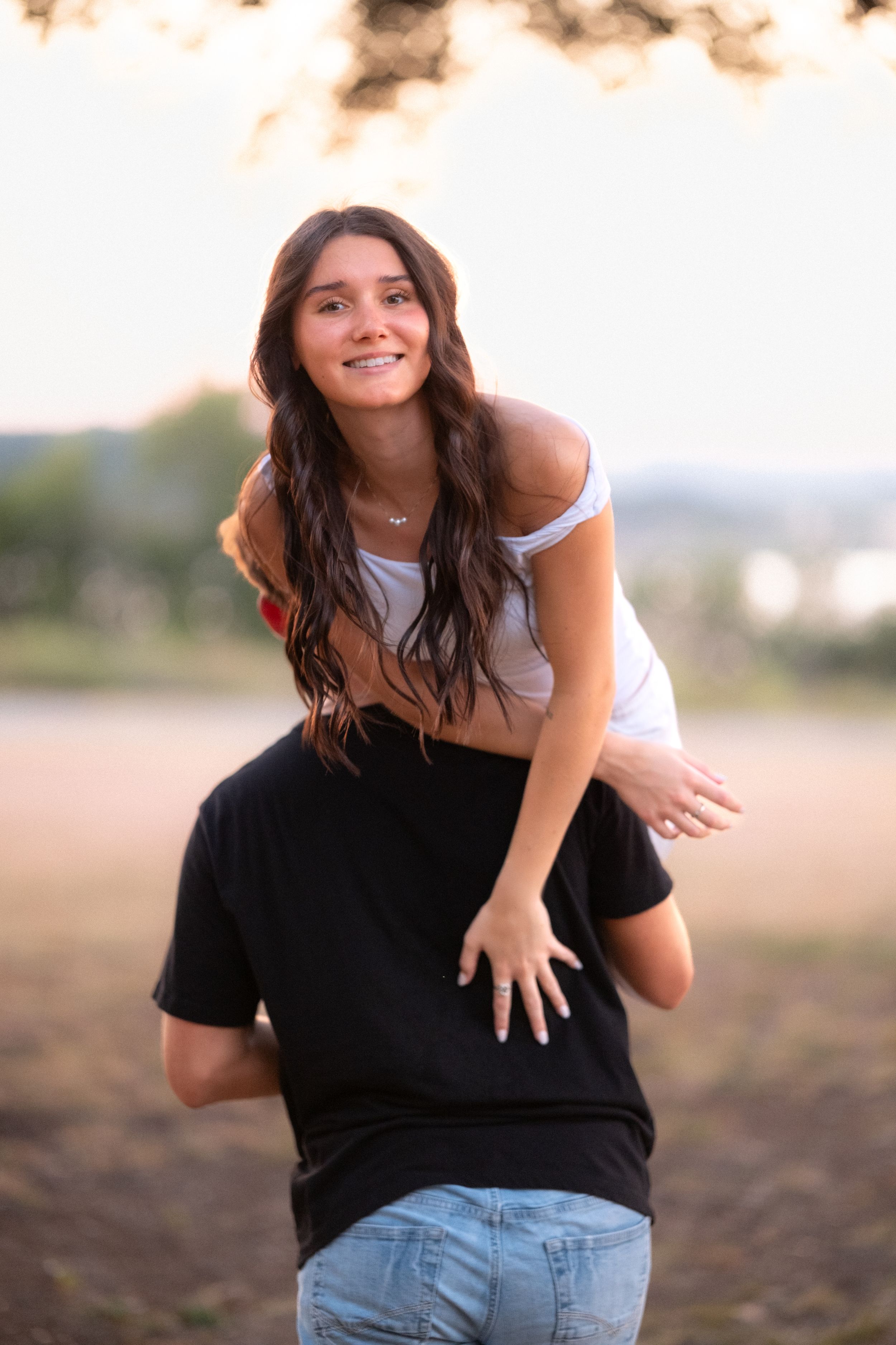 Young woman smiling joyfully while being lifted by her partner in an outdoor field at sunset  in Belton Texas