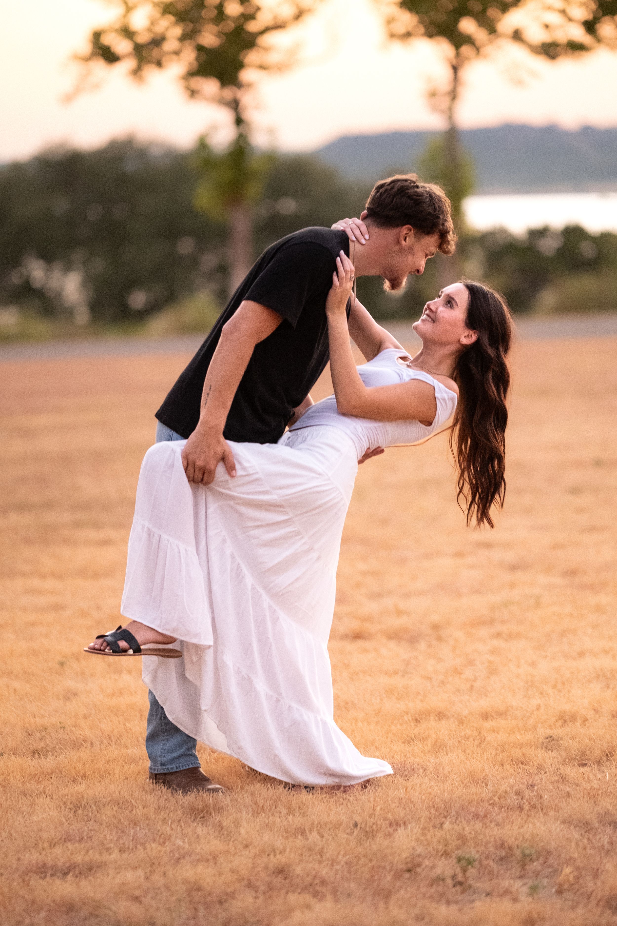 Romantic couple dancing and dipping in a golden field at sunset near a peaceful lake in Belton Texas