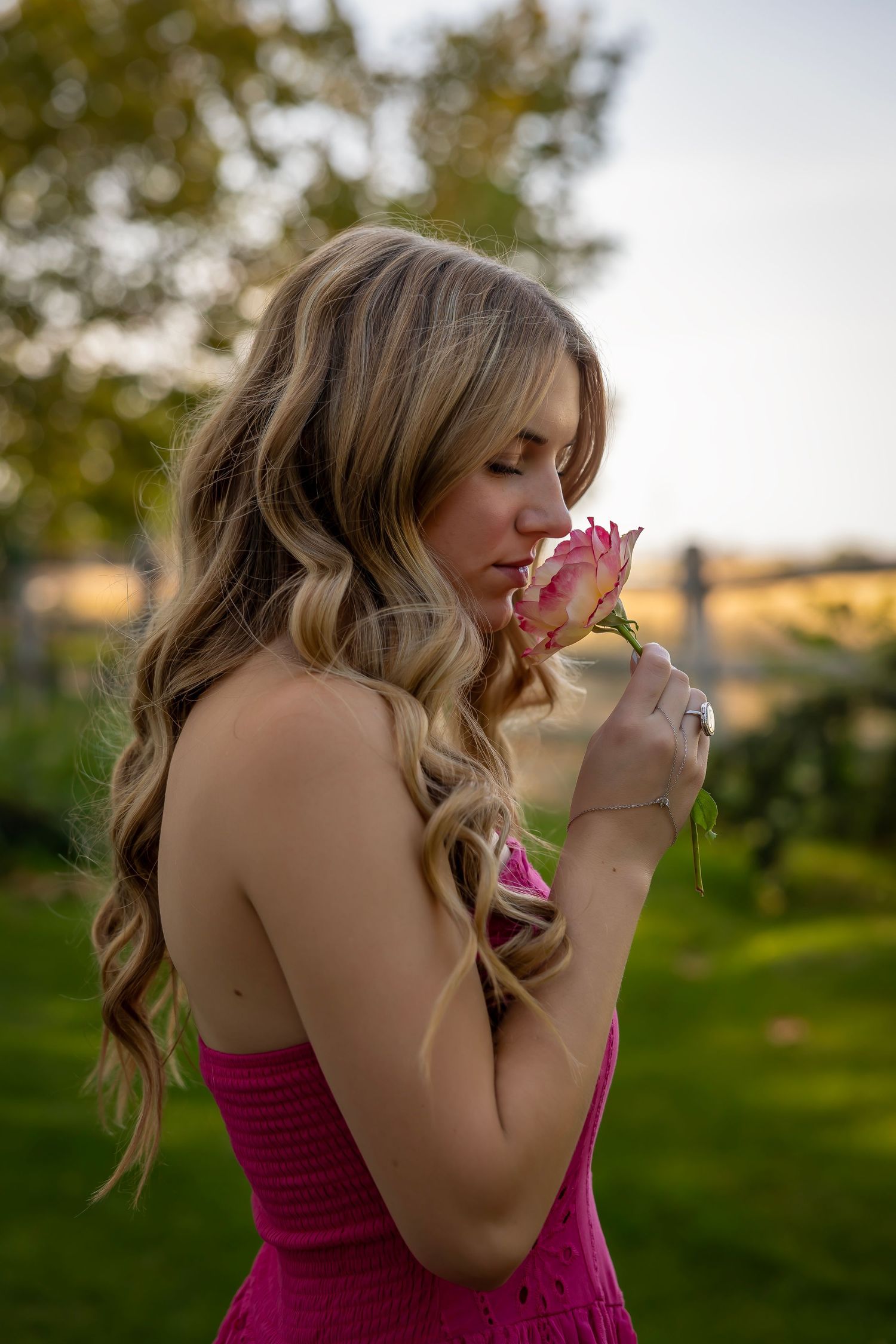Girl with pink dress smelling a rose