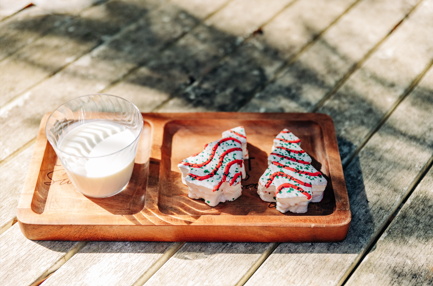 Two festive onigiri rice balls decorated with red and blue icing on a wooden tray with a glass of milk.