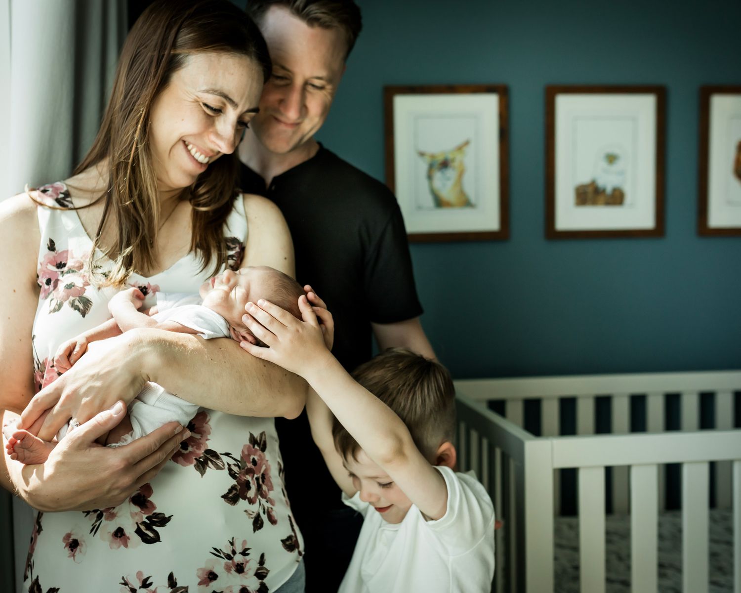 Parents cuddling their newborn baby with big brother in their Calgary home during an in-home newborn photography session