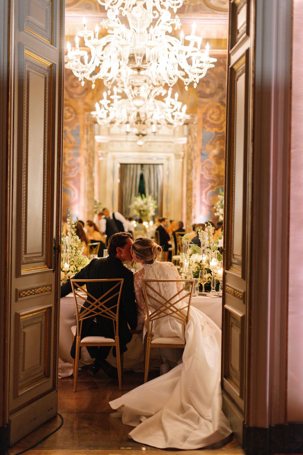 Bride and groom share an intimate moment at their elegant wedding reception in a grand ballroom with crystal chandeliers.