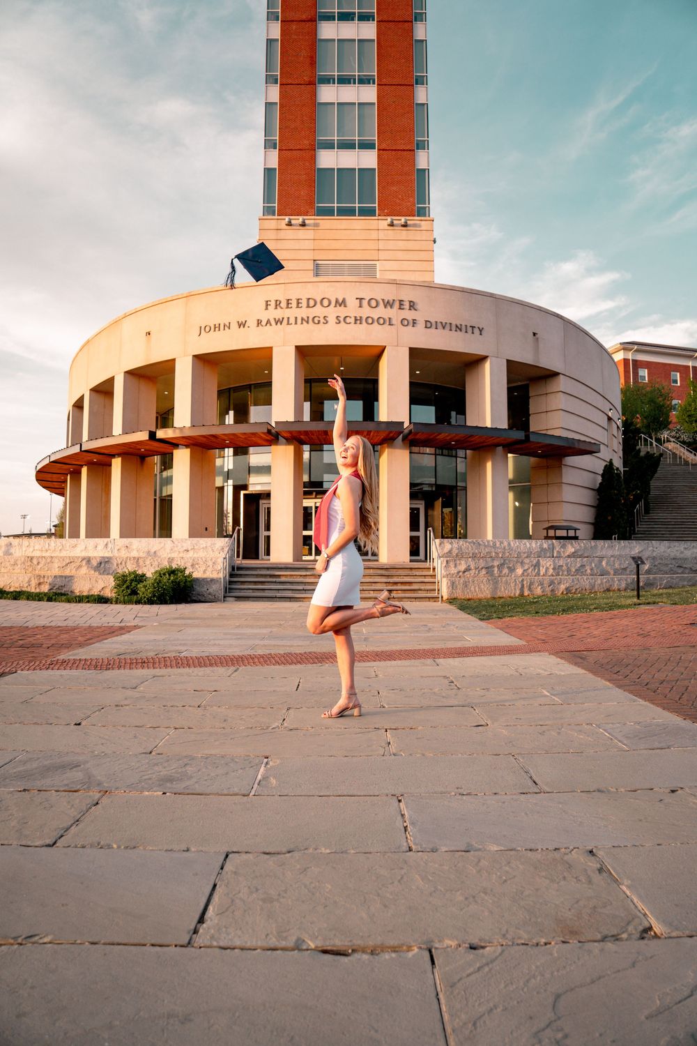 Woman in white dress dancing ballet pose in front of Freedom Tower, John W. Rawlings School of Divinity.