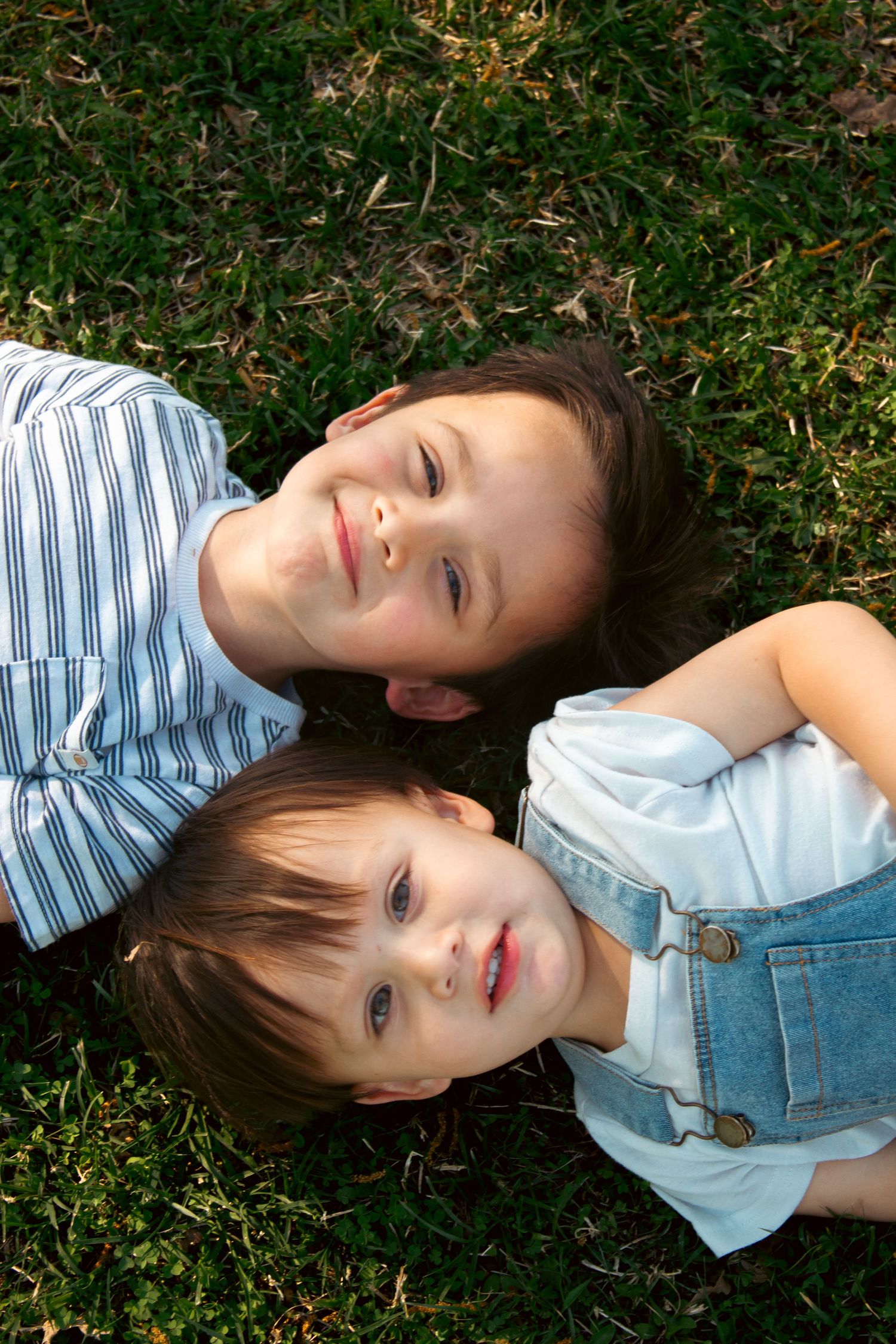 two young boys lying on their backs in the grass during a childhood session in Blytheville Arkansas