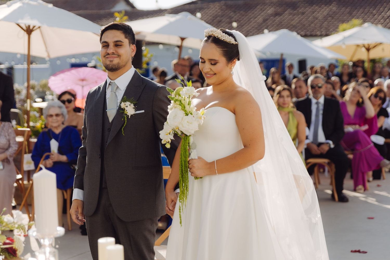 Bride and groom walk down the aisle together at sunny outdoor wedding ceremony.