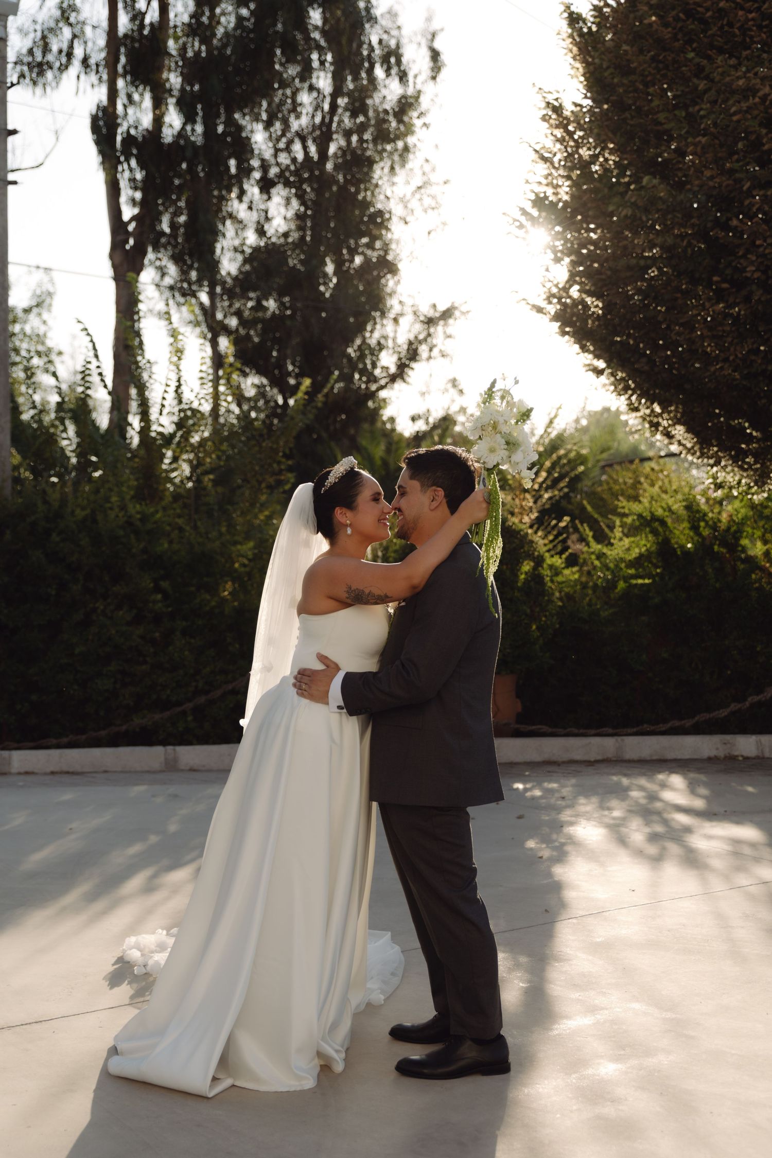 Wedding couple sharing a tender moment in a sunlit outdoor garden setting.