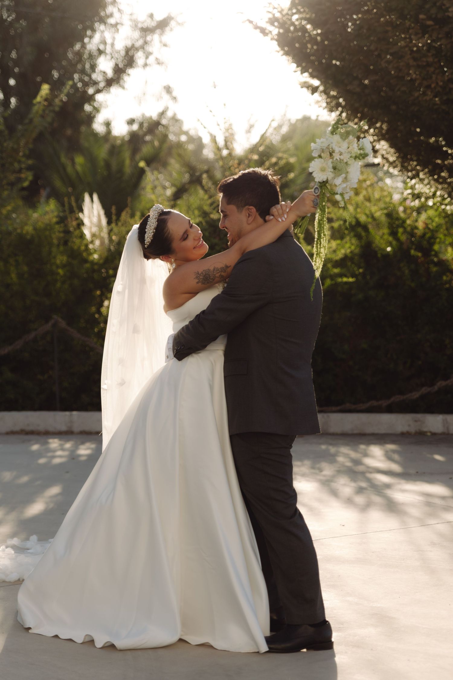 Bride and groom embracing in a golden sunset garden on their wedding day.