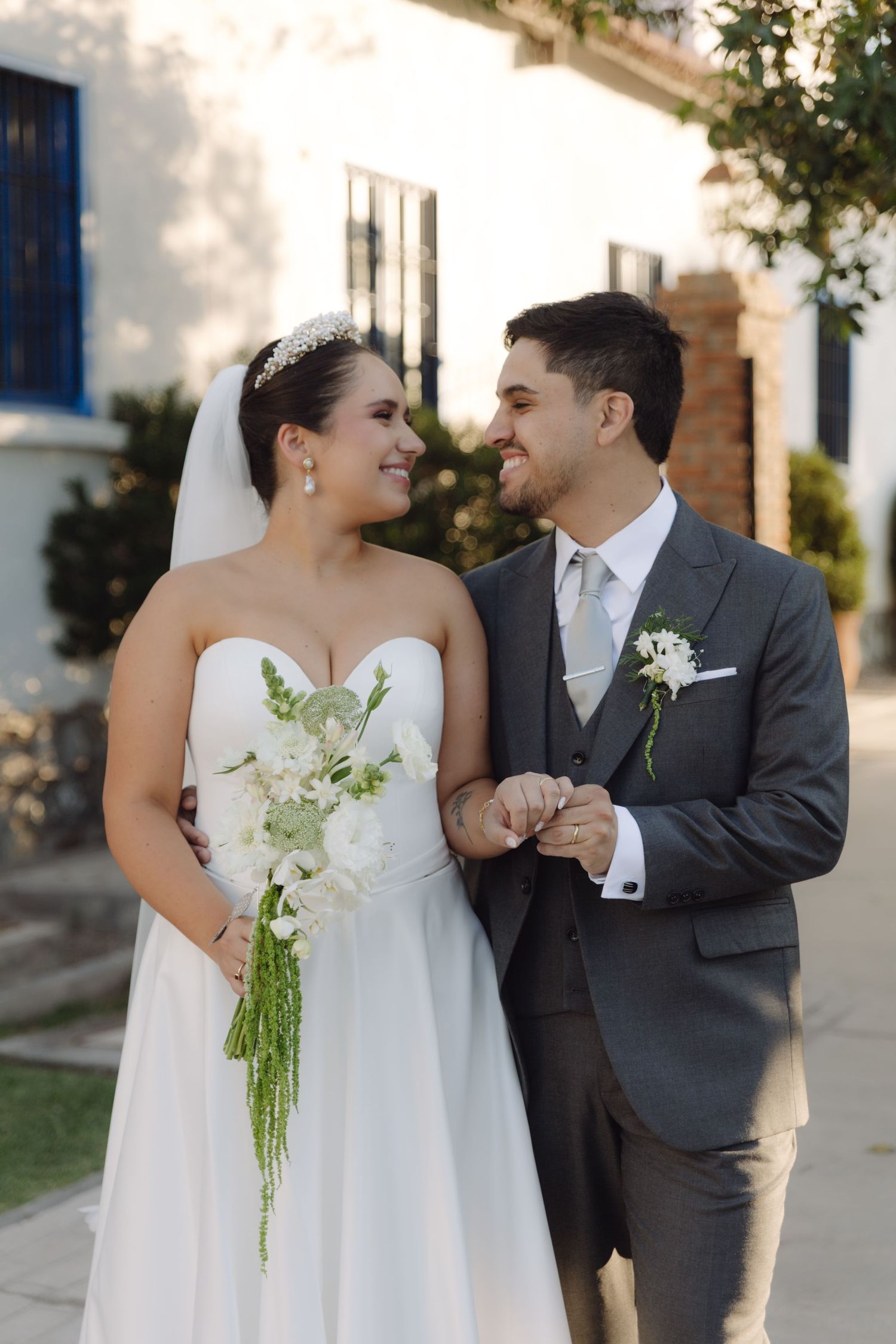 Happy bride and groom gazing at each other while holding a white bouquet.