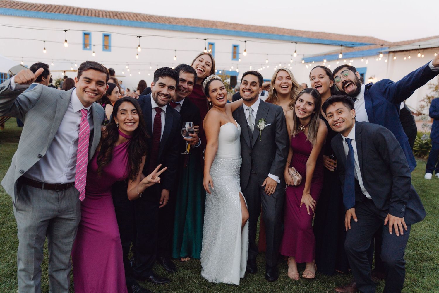 Bride and groom take a fun group selfie with friends at an outdoor wedding celebration.