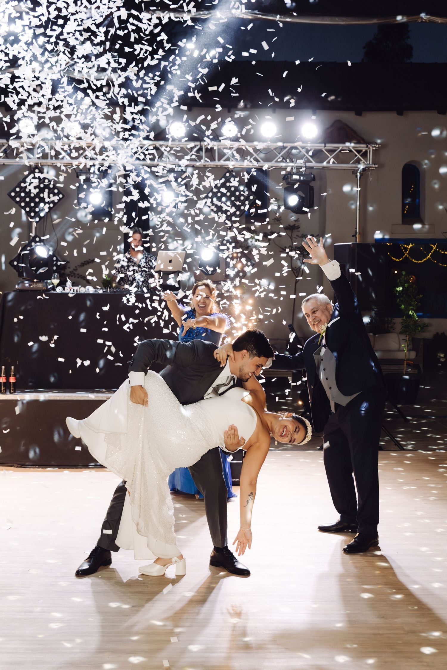 Newlyweds perform an elegant dip on the dance floor with sparkling confetti raining down around them.