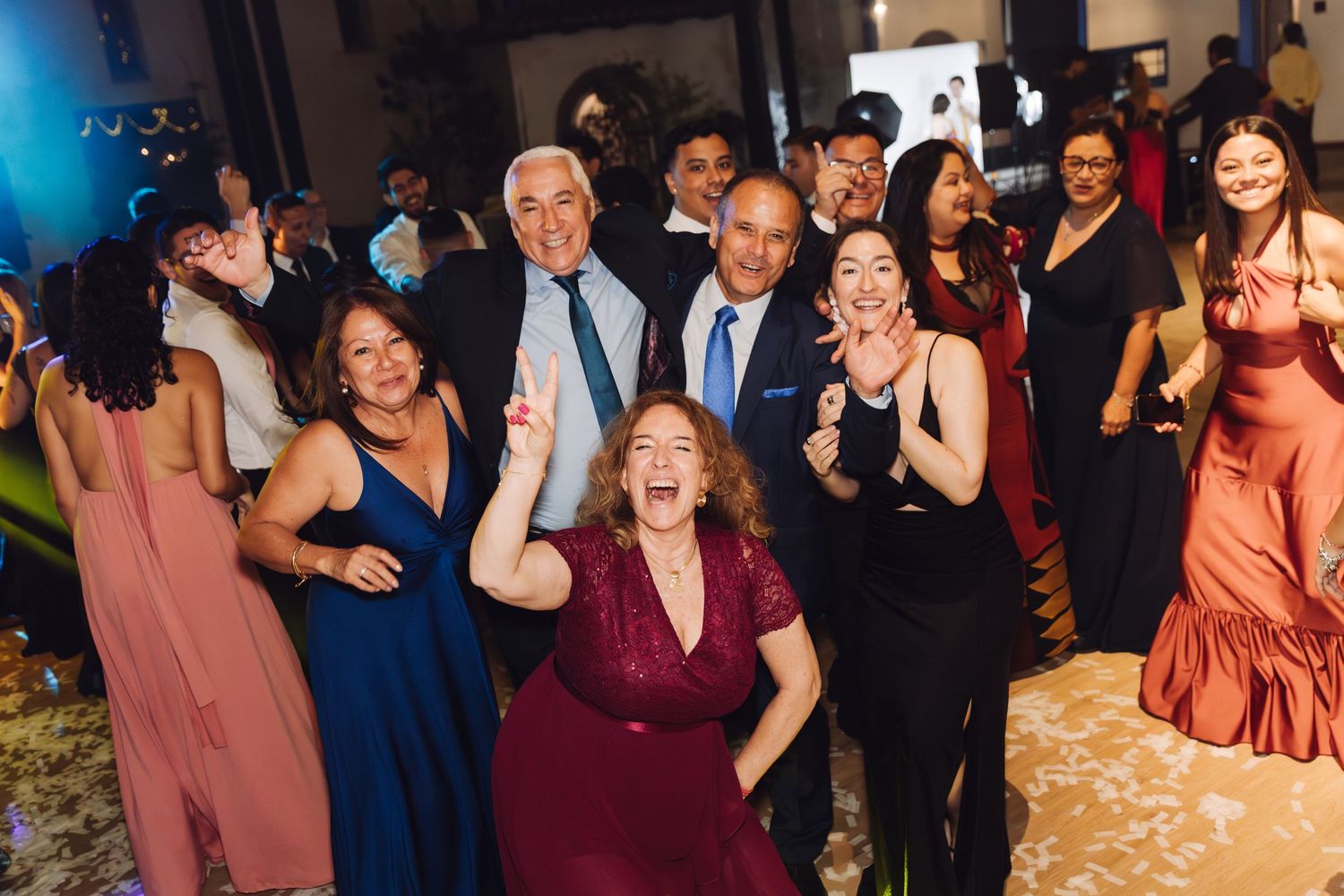 Joyful wedding guests dancing and celebrating together on the dance floor at an elegant indoor reception.