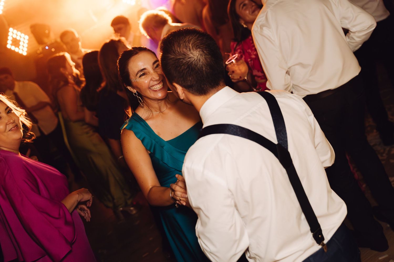 Couple sharing a romantic dance at a wedding reception under warm golden lighting.
