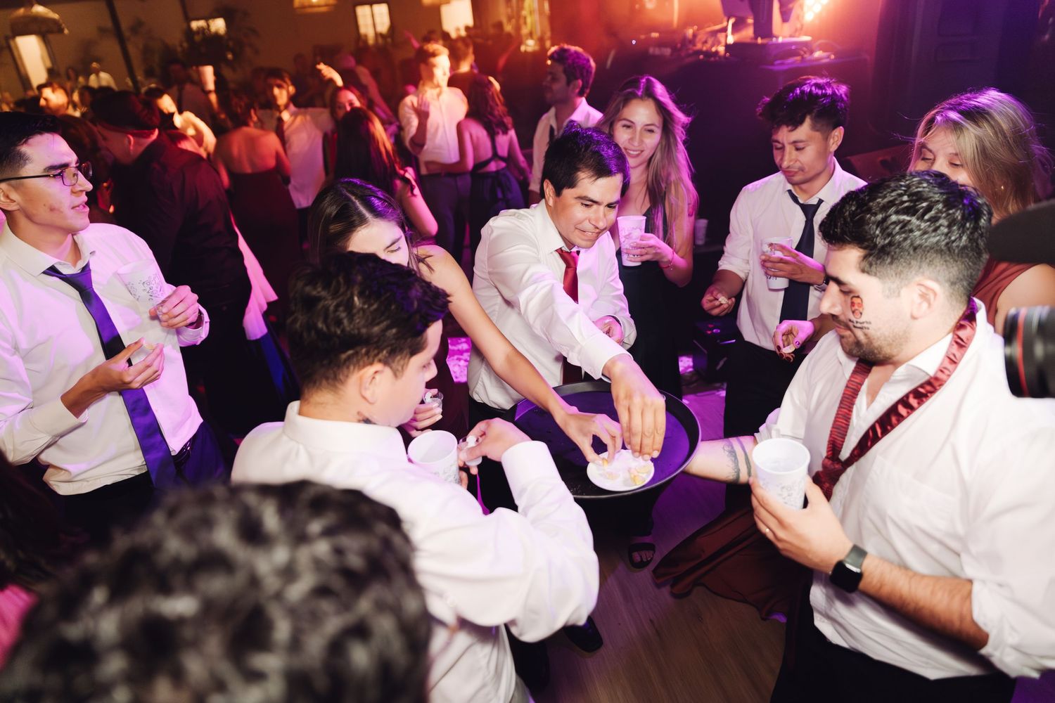 Young men in white shirts playing a party game together on the wedding dance floor.