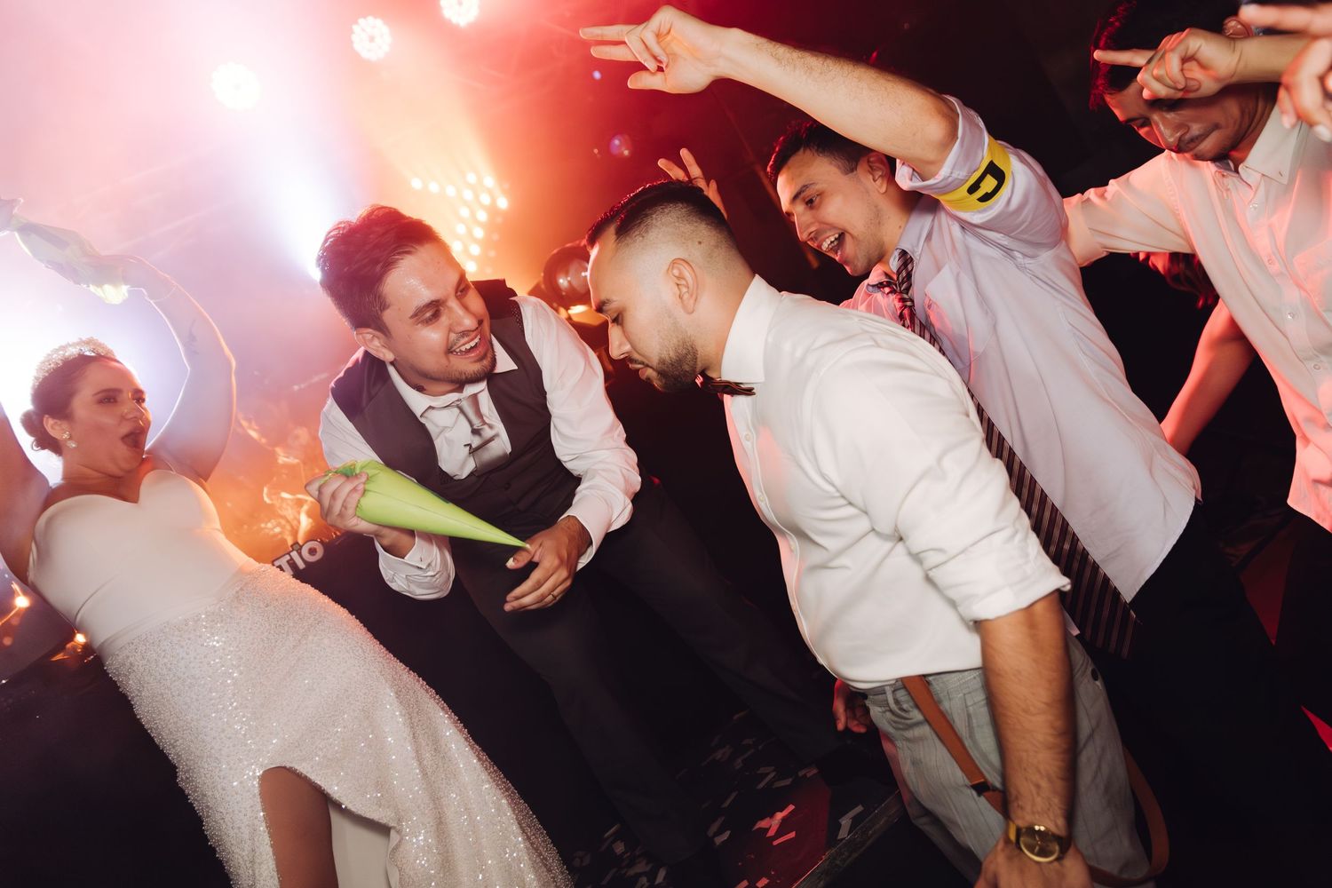 Wedding guests celebrating with sparklers and dancing on a colorful illuminated dance floor.