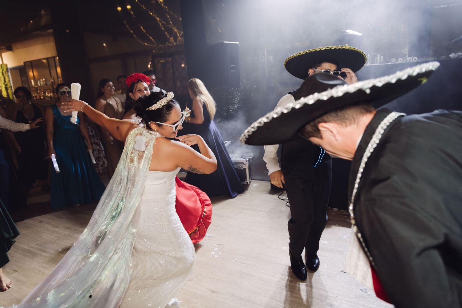 Bride dancing with mariachi band performers in sombreros at wedding reception.
