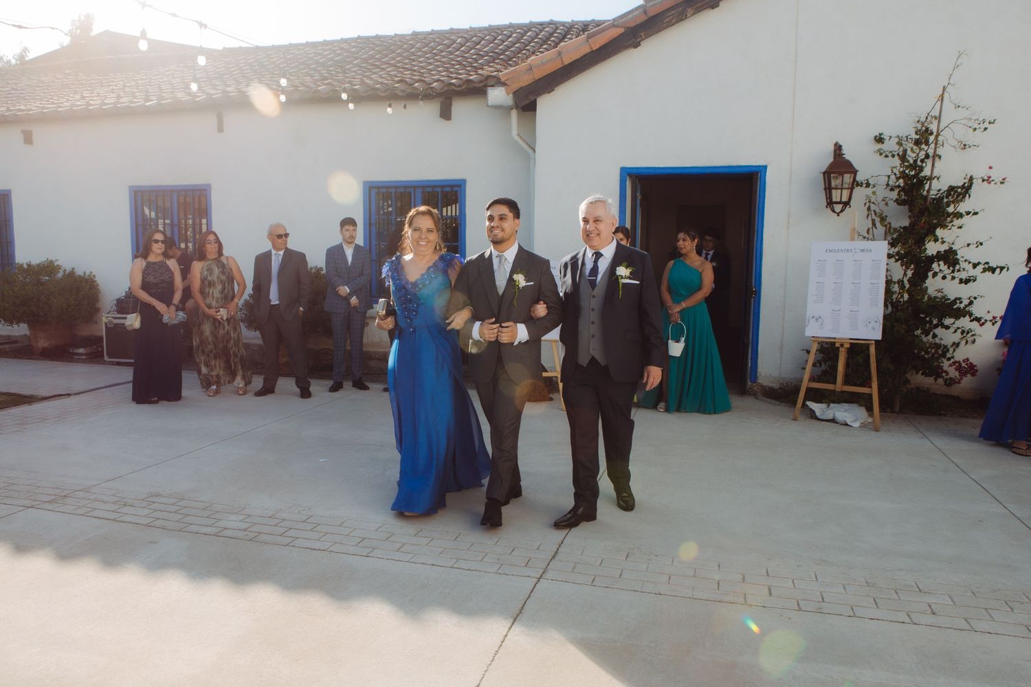 Wedding processional with couple walking down outdoor aisle flanked by guests.