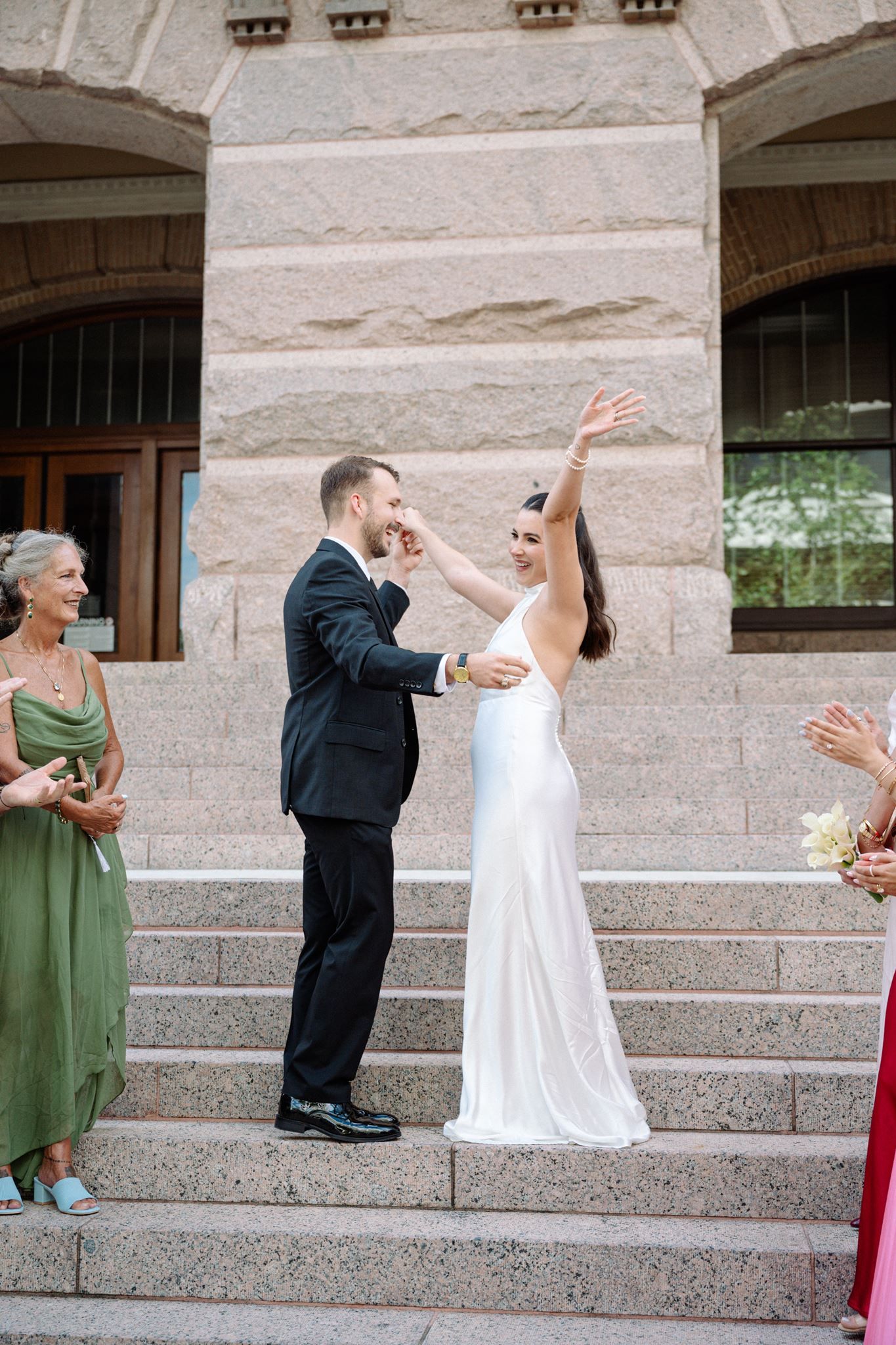 Bride and groom cheering on the steps of the historic Houston Courthouse.