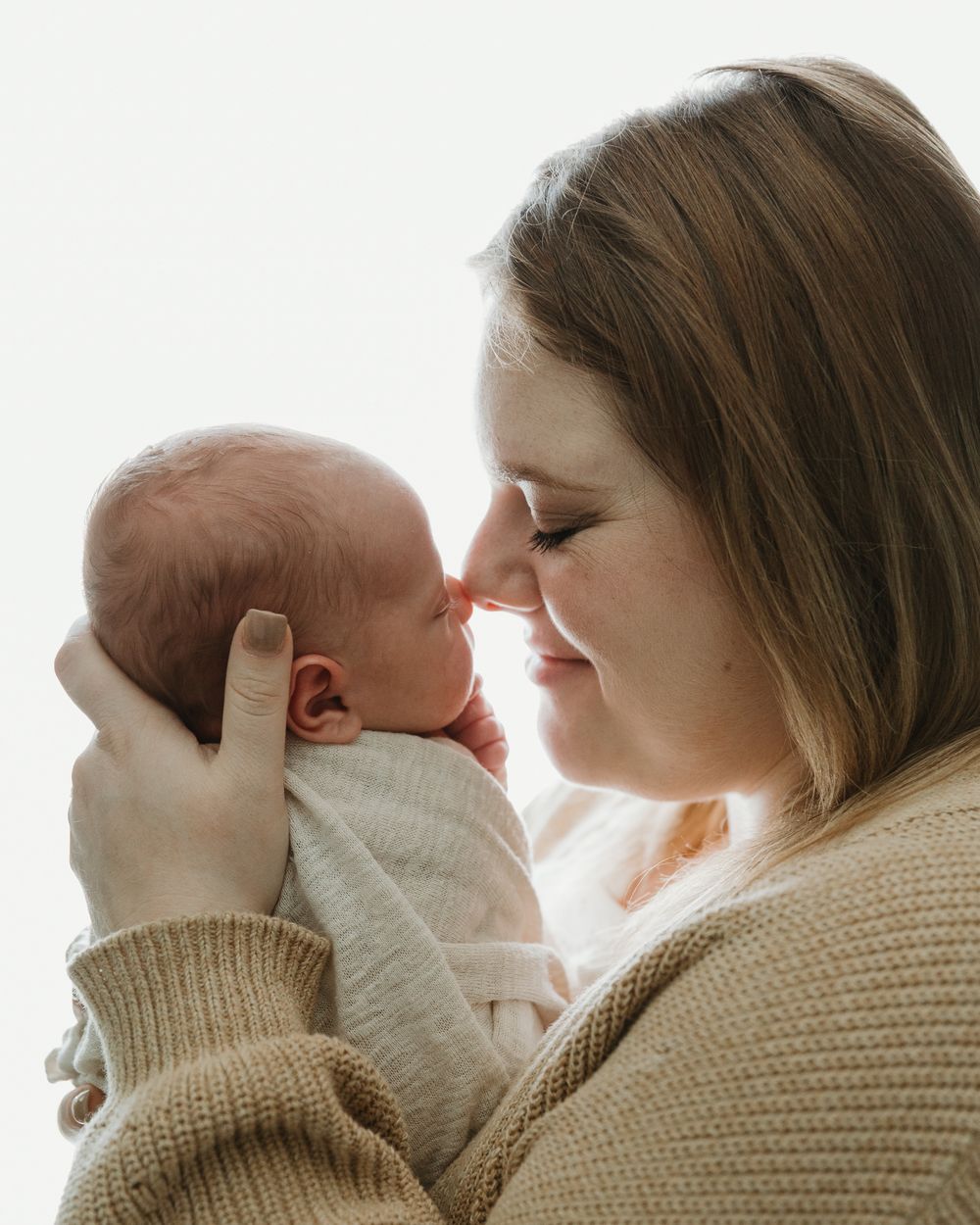 glowing image of mom nose to nose with newborn during in home newborn photography session with Tyler Tx newborn Motherhood photographer