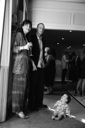 A couple with a baby at a formal event, woman holding champagne glass in black and white photo.