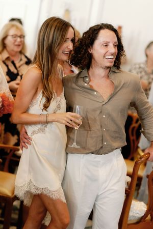 Couple laughing and holding champagne glasses at a wedding celebration, bride in white lace dress.