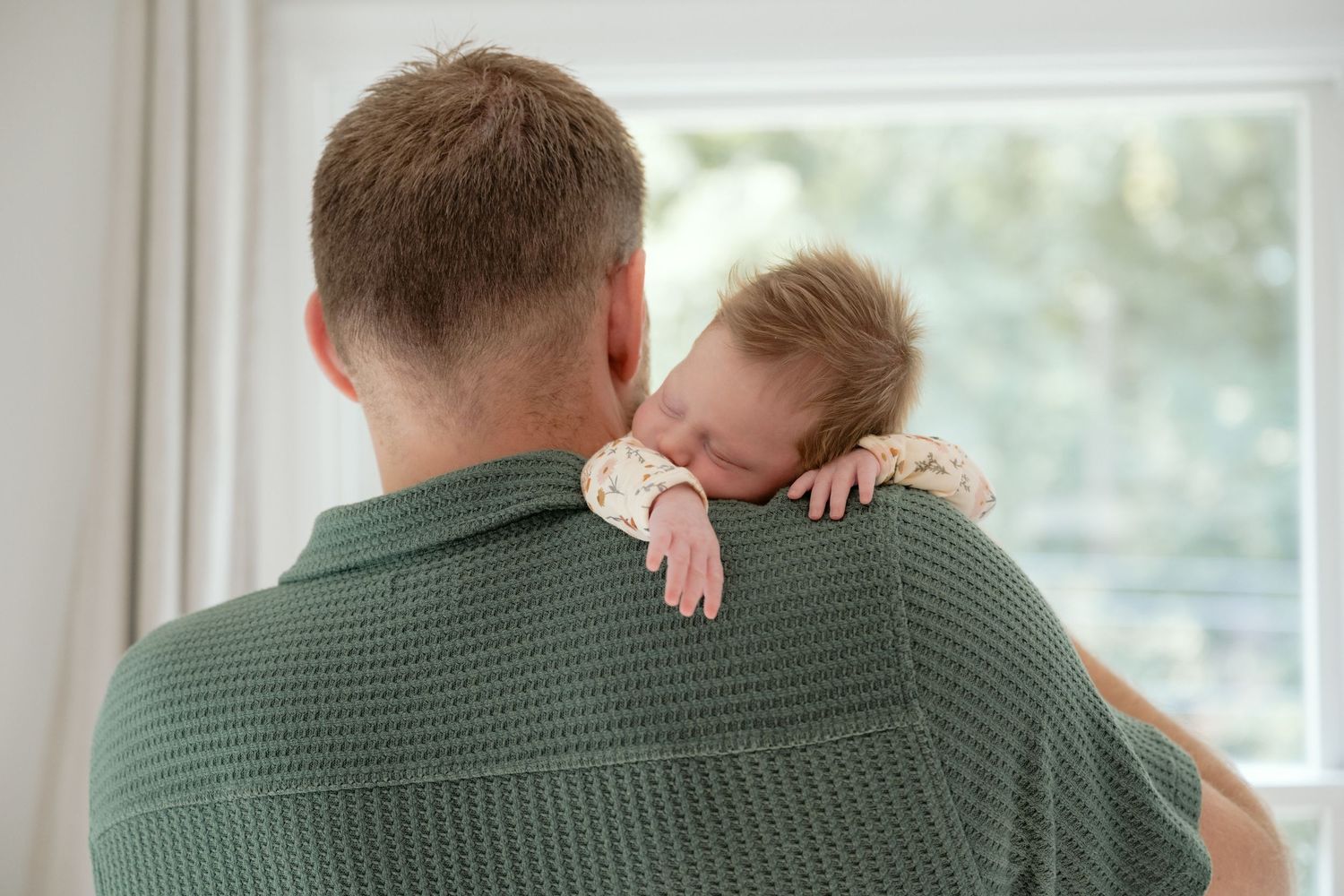 Sleeping newborn baby hanging over dad's shoulder during in-home newborn session in the Minnetonka/Hopkins area.