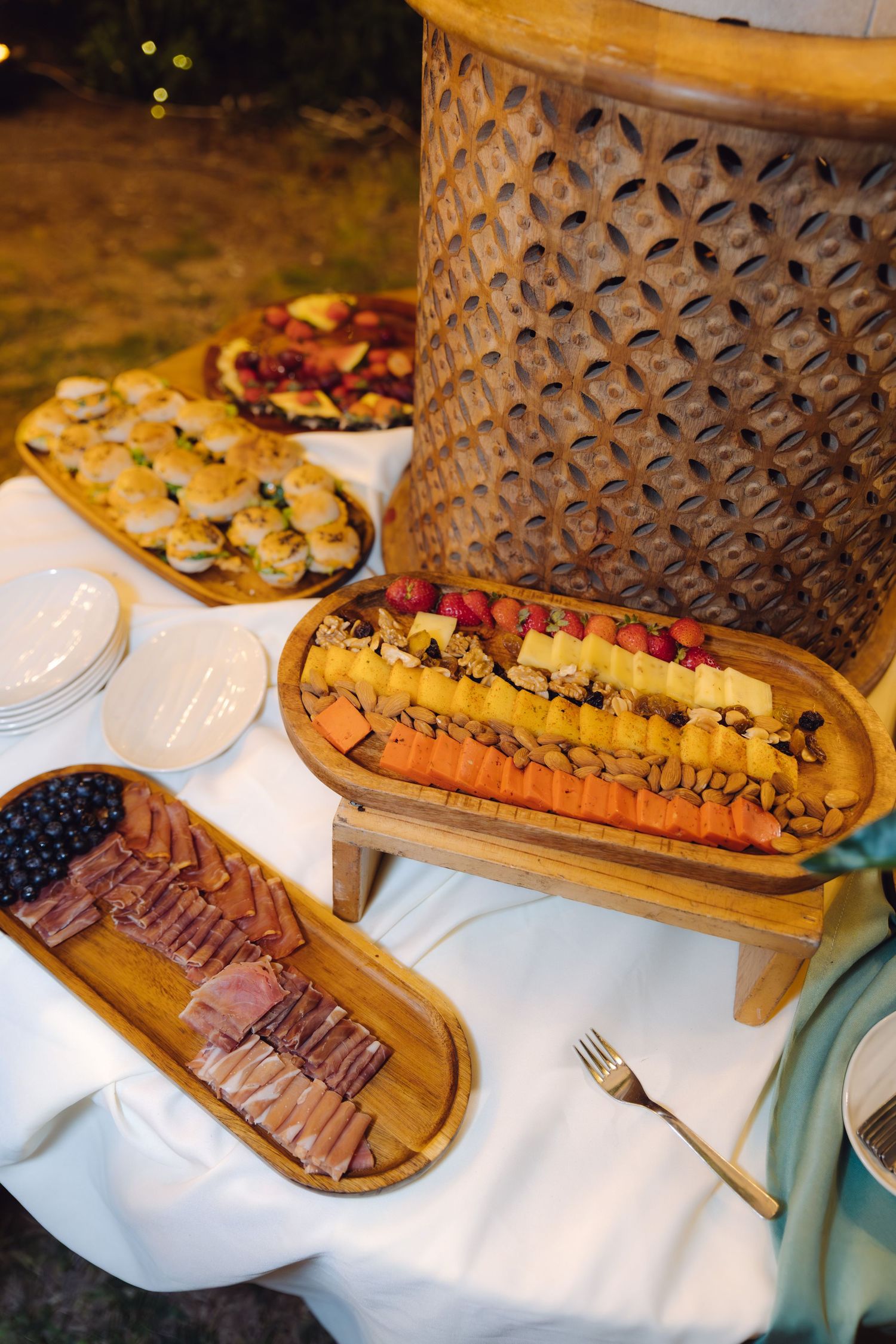 Elegant wedding charcuterie spread with cheese, fruit, and meats on wooden boards.