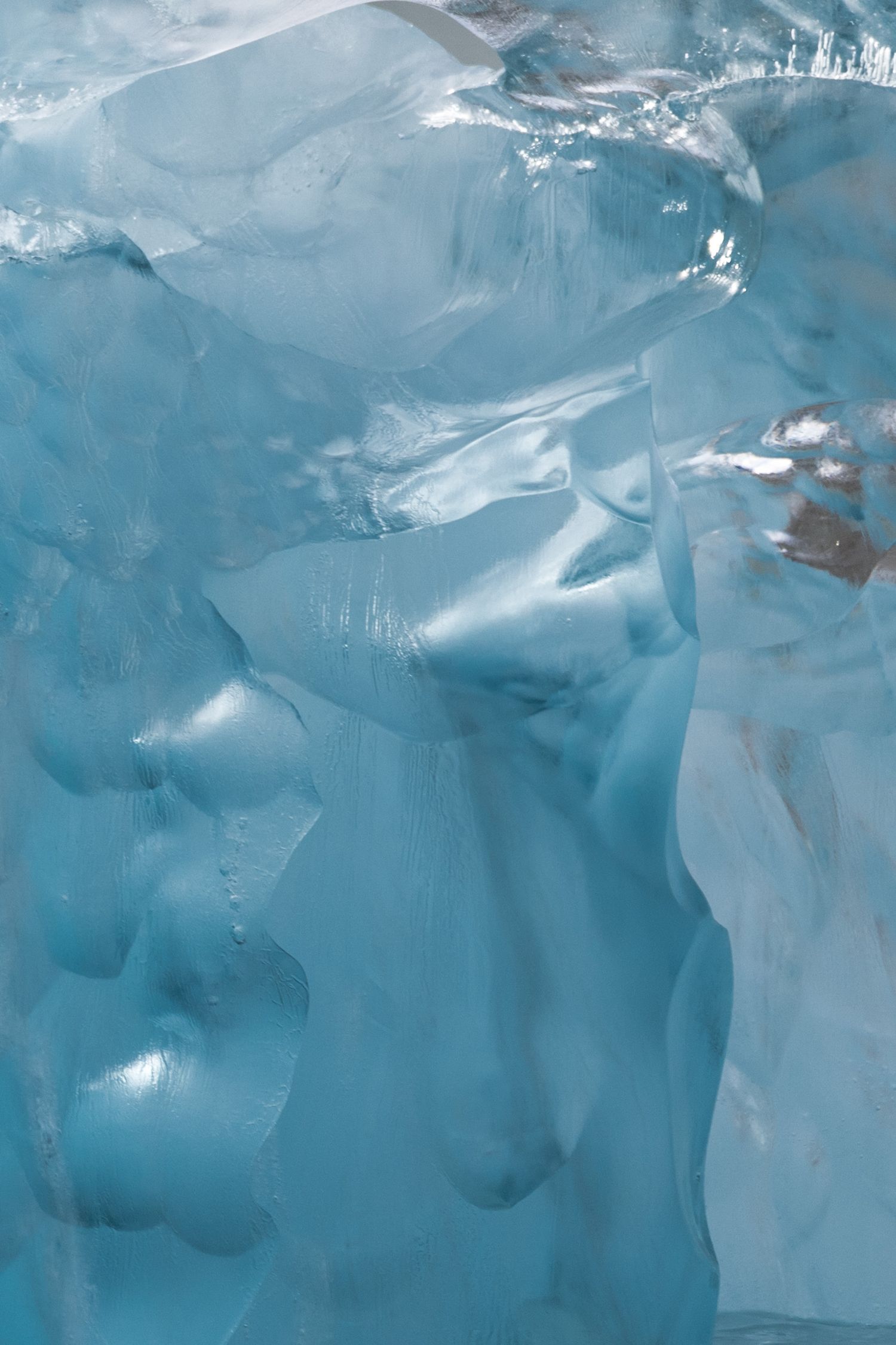 Surface polie et translucide de glace ancienne bleu clair traversée d'éclats de lumière