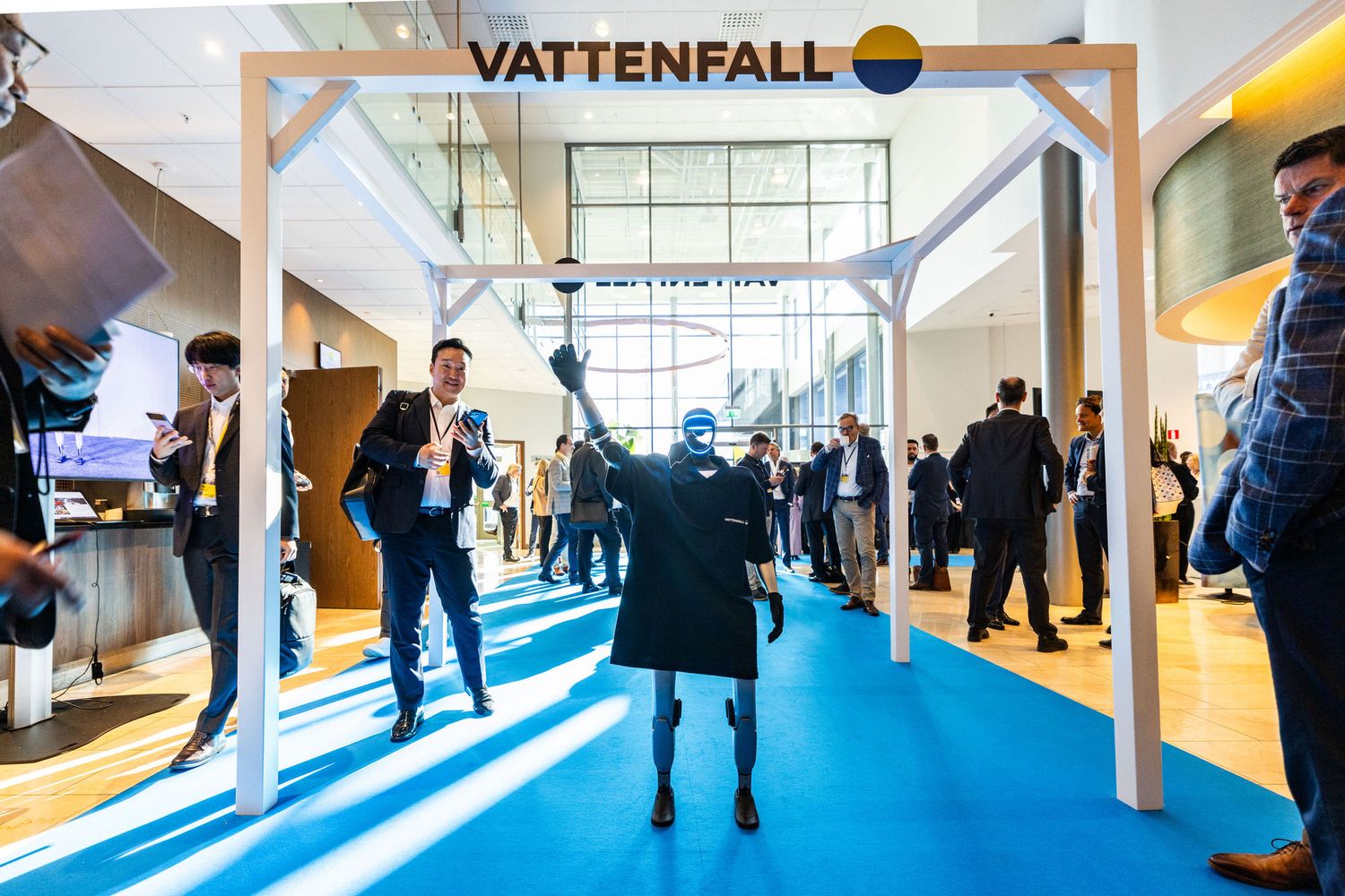 Business professionals walk through Vattenfall branded entrance arch at an industry expo.