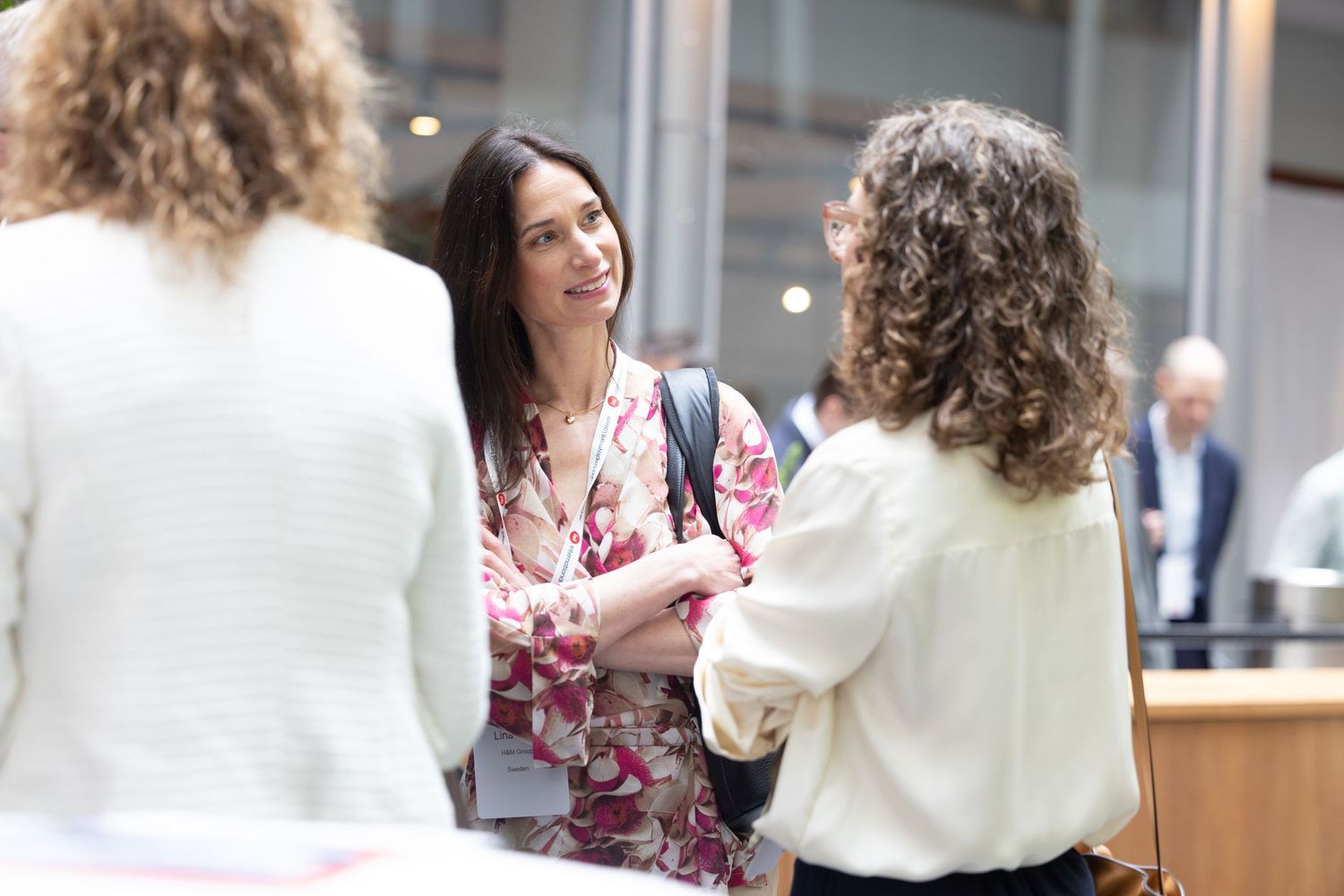 Two professional women engage in a warm conversation during a networking break at a business conference.