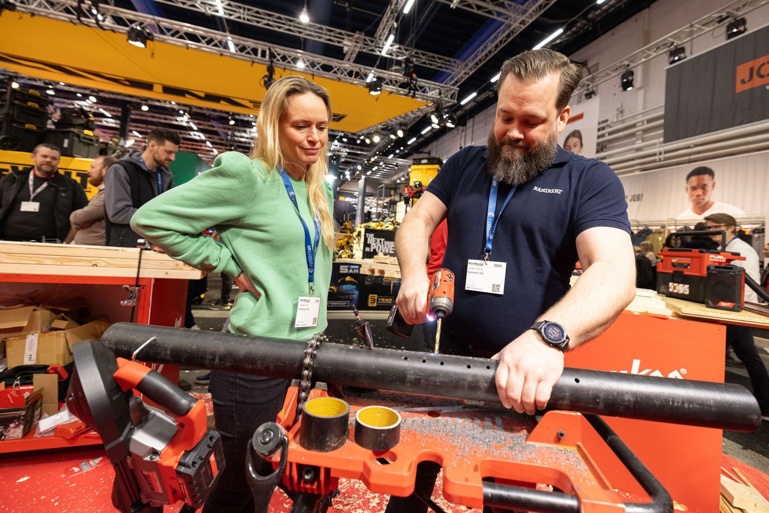 Two attendees examining industrial equipment at a hands-on trade show exhibition floor demonstration.