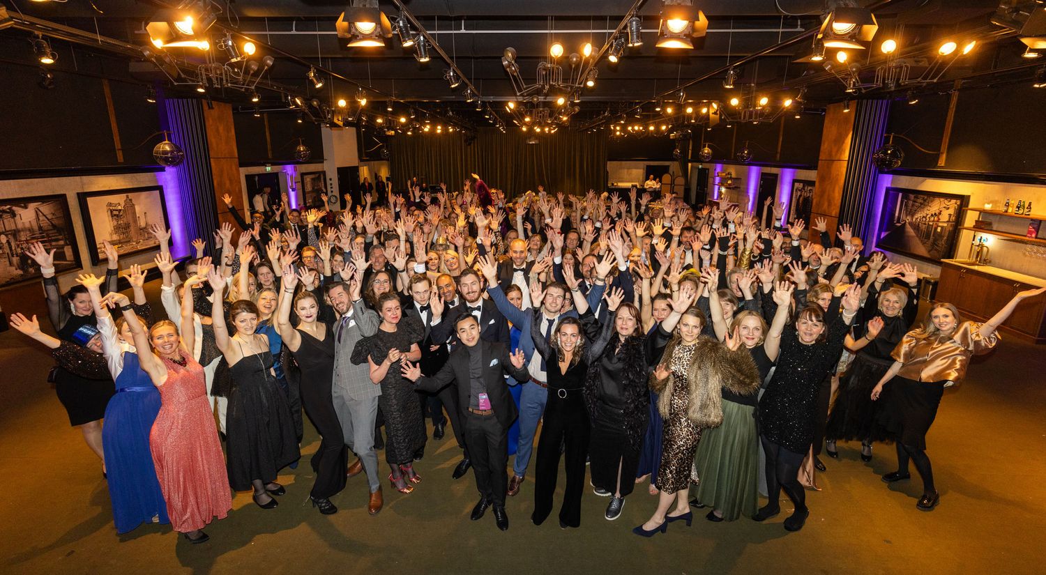 Large group of formally dressed event attendees celebrate together at an awards ceremony.