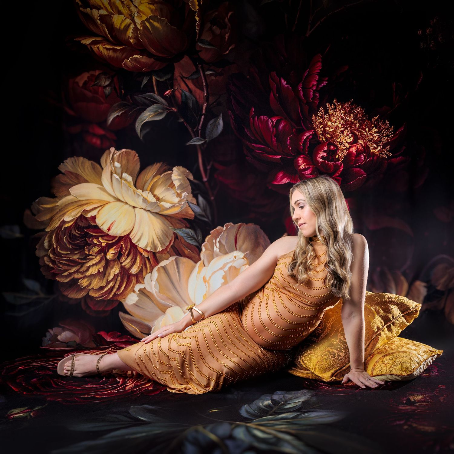 Pregnant momma-to-be sits looking stunning against sophisticated backdrop of burgundy and gold flowers.