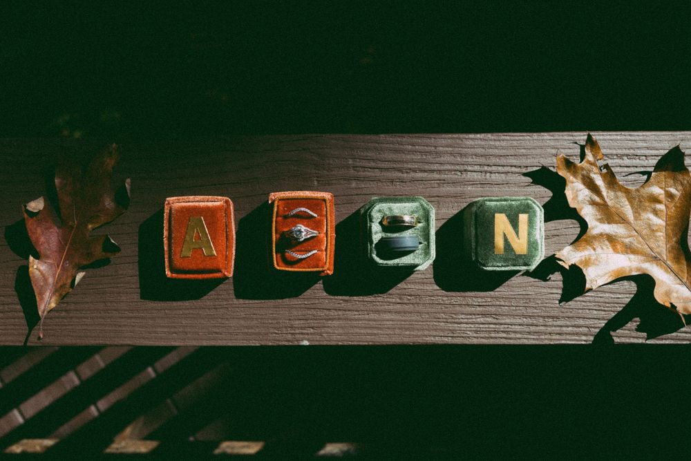 Decorative wooden letter blocks spelling AEON arranged on dark wood surface with autumn oak leaves.