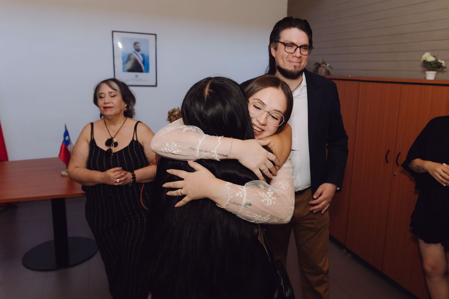 Bride and groom share emotional moment as guests embrace and celebrate at civil wedding ceremony.