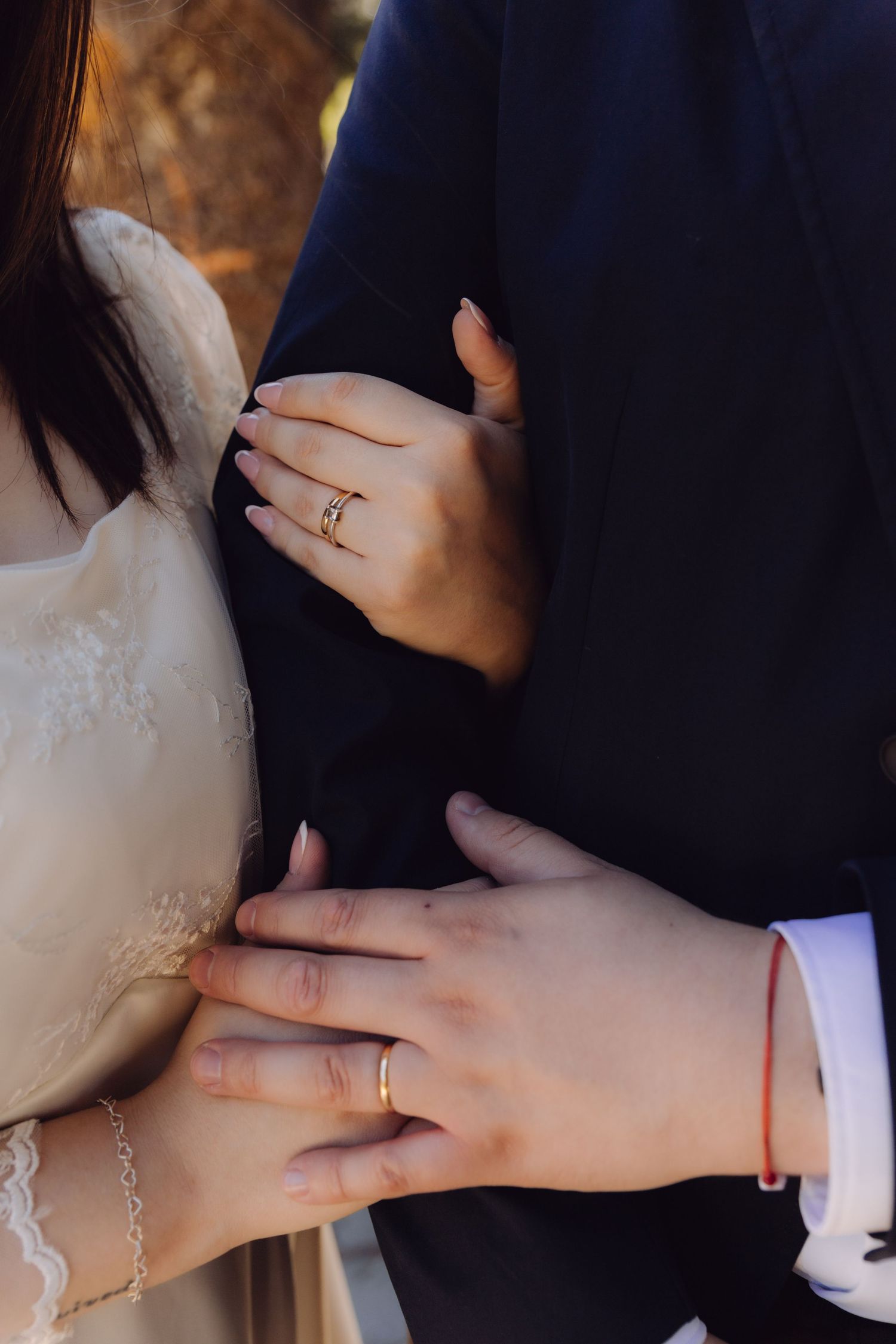 Close-up of bride and groom hands showing gold wedding rings during ceremony.